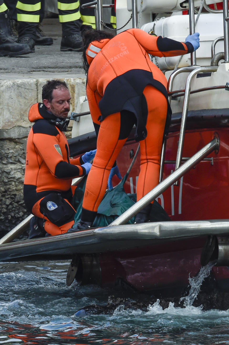 Italian firefighter divers bring ashore in a green bag the body of one of the victims of the UK flag vessel Bayesian, Wednesday, Aug. 21, 2024. The luxury sail yacht was hit by a violent sudden storm and sunk early Monday, while at anchor off the Sicilian village of Porticello near Palermo, in southern Italy. (AP Photo/Salvatore Cavalli)