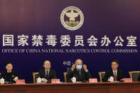 Deng Ming, deputy director of China's National Narcotics Control Commission, center removes his mask for a press conference in Beijing on Tuesday, May 11, 2021. China on Tuesday said it will add all synthetic cannabinoids to its list of banned drugs, in what it described as a first in the world, to curb their manufacturing, trafficking and abuse. (AP Photo/Ng Han Guan)