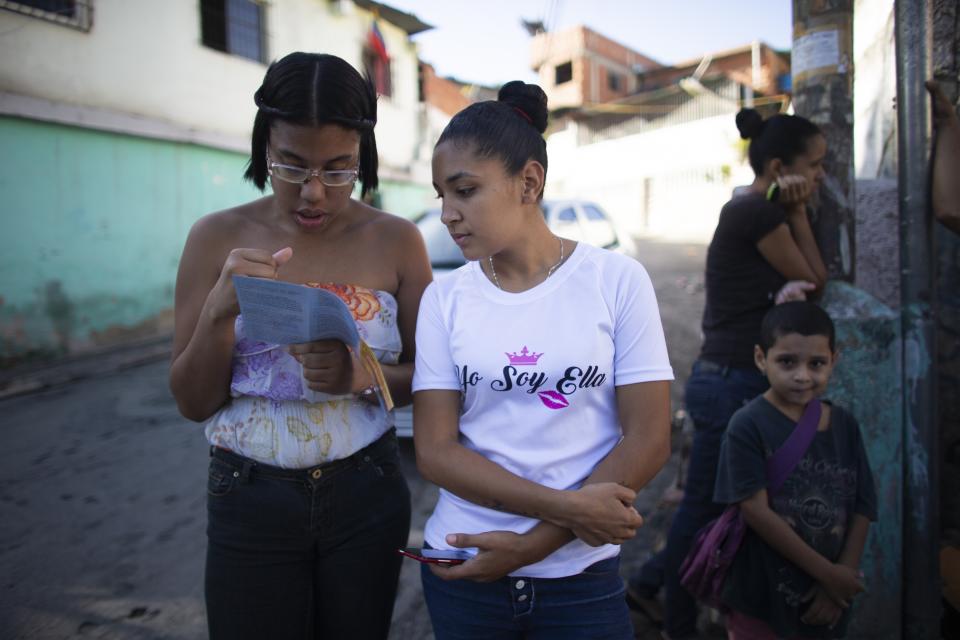 In this photo taken July 25, 2019, young women read a brochure about hormonal implants outside a clinic where a very limited number are being administered in the Caucaguita neighborhood on the outskirts of Caracas, Venezuela. “Women are getting pregnant and don’t have options,” said Luisa Kislinger, a women’s rights activist. “They’re forced into motherhood.” (AP Photo/Ariana Cubillos)