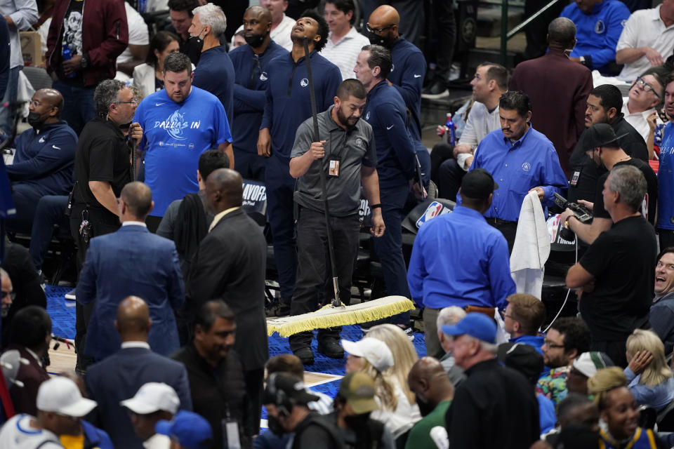 Officials help soak up a rain leak from the American Airlines Center roof during the second half of Game 4 of the NBA basketball playoffs Western Conference finals between the Dallas Mavericks and the Golden State Warriors, Tuesday, May 24, 2022, in Dallas. (AP Photo/Tony Gutierrez)