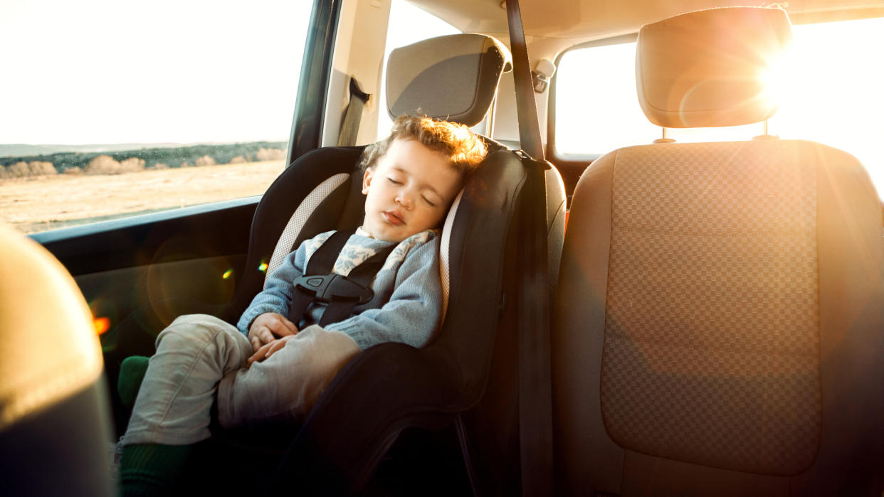 Smiling little boy sitting car in child seat.