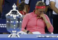 Victoria Azarenka of Belarus wipes her face as she sits by the winner's trophy (L) after being defeated by Serena Williams of the U.S. in their women's singles final match at the U.S. Open tennis championships in New York September 8, 2013. REUTERS/Eduardo Munoz (UNITED STATES - Tags: SPORT TENNIS)