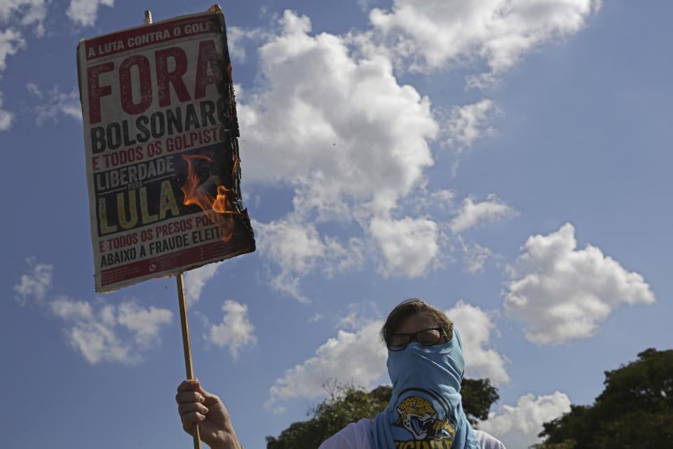 A masked student burns a poster with a message that reads in Portuguese: "Out Bolsonaro" during an education strike in Brasilia, Brazil, Wednesday, May 15, 2019. Federal education officials this month announced budget cuts of $1.85 billion for public education, part of a wider government effort to slash spending. (AP Photo/Eraldo Peres)