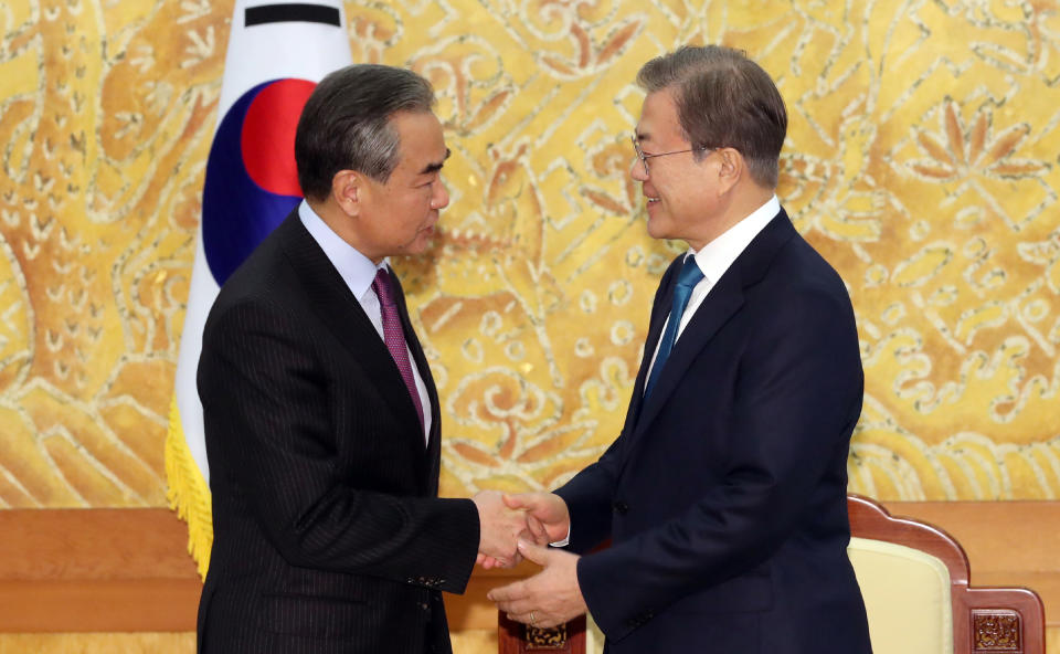 South Korean President Moon Jae-in, right, greets Chinese Foreign Minister Wang Yi during a meeting at the presidential Blue House in Seoul, South Korea, Thursday, Dec. 5, 2019. Wang arrived in South Korea on Wednesday for his first visit in four years amid efforts to patch up relations damaged by Seoul's decision to host a U.S. anti-missile system that Beijing perceives as a security threat. (Lee Jin-wook/Yonhap via AP)