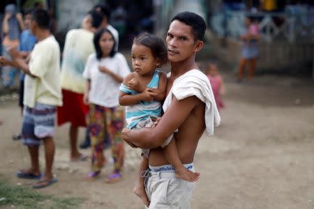 An evacuated resident carries a child at an evacuation centre in Iligan, while government forces fight insurgents from the Maute group in Marawi, Philippines June 27, 2017. REUTERS/Jorge Silva