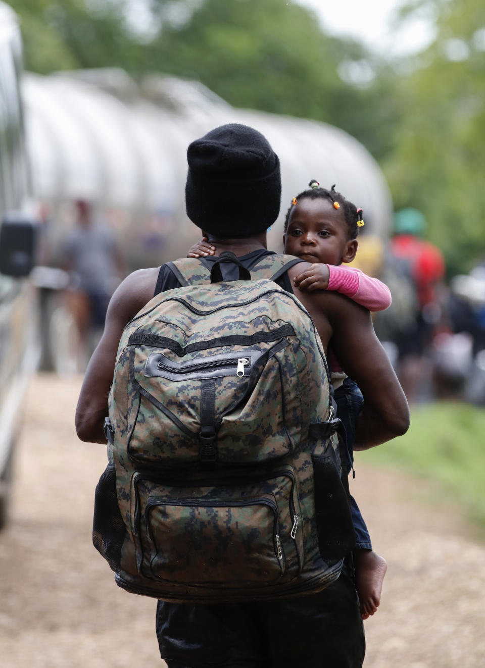 A migrant man carrying a child arrives at a shelter in Lajas Blancas, Darien, Panama, Saturday, Oct. 23, 2021. A rising number of female migrants have reported suffering sexual abuse while crossing the treacherous Darien Gap between Colombia and Panama. Seeking to draw attention to the issue, a group of Panamanian lawmakers travelled Saturday on a fact-finding mission to speak with victims and authorities in the remote province. (AP Photo/Ana Renteria)