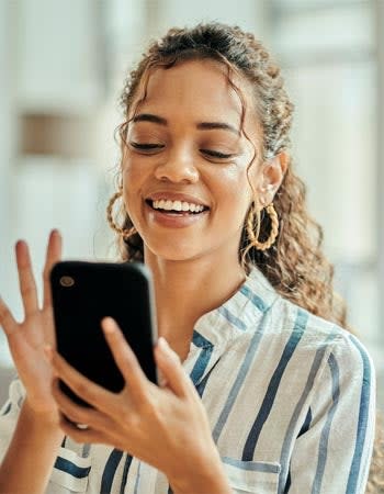 A woman smiles while looking at her phone. 