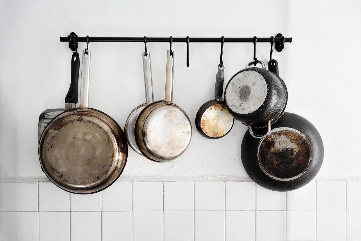 Pots and pans hanging on a kitchen wall Getty Images/Carlina Teteris