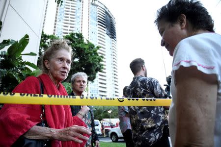 Karen Hastings (L), who was evacuated from the floors where the fire broke out at Marco Polo apartment building, talks with another resident, in Honolulu, Hawaii, July 14, 2017. REUTERS/Hugh Gentry