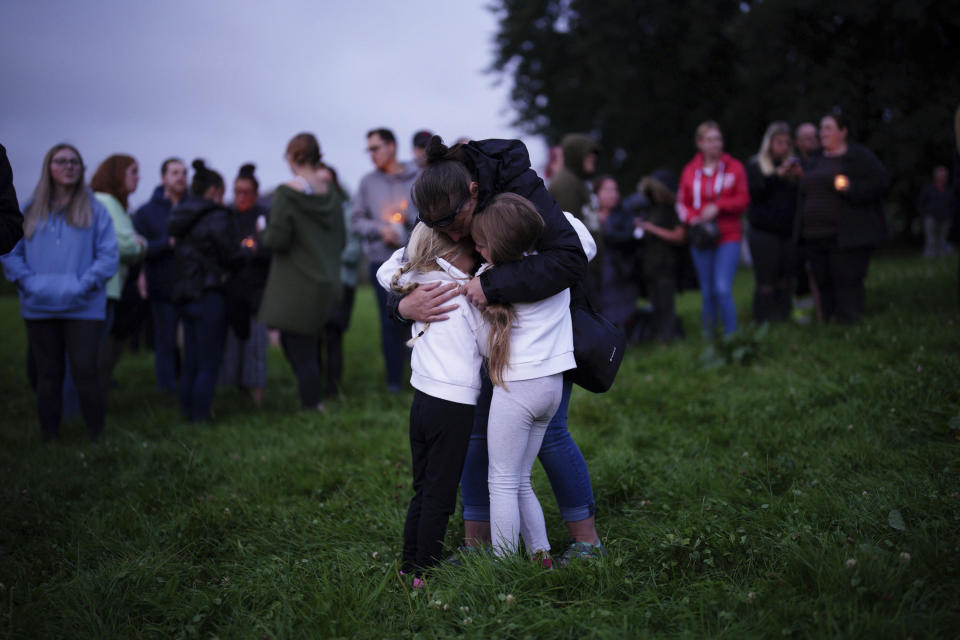 A woman embraces two children during a vigil for the victims of the Keyham mass shooting in Plymouth, England, Friday Aug. 13, 2021. Six people, including the offender, died of gunshot wounds in a firearms incident on Thursday evening. The police have said the gunman killed his own mother along with a three-year old girl and her father. (Ben Birchall/PA via AP)