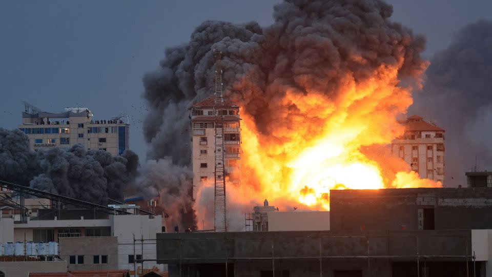 People standing on a rooftop watch fire and smoke rise from an Israeli strike above a building in Gaza City, on October 7. - Mahmud Hams/AFP/Getty Images