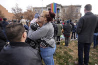 Onlookers embrace after a 25-foot historic pride flag was displayed on the exterior of city hall to mark the weekend mass shooting at a gay nightclub Wednesday, Nov. 23, 2022, in Colorado Springs, Colo. (AP Photo/David Zalubowski)