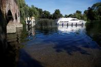 A boat passes under a bridge where water levels are low on the River Thames in Sonning