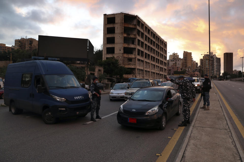 Police officers stand at a checkpoint to inspect cars that violate the lockdown during an 11-day nationwide shutdown aimed at curbing the spread of the coronavirus, in Beirut, Lebanon, Friday, Jan. 15, 2021. Lebanon's parliament has approved a draft law to allow the importing of vaccines into the tiny country to fight the spread of coronavirus. (AP Photo/Bilal Hussein)