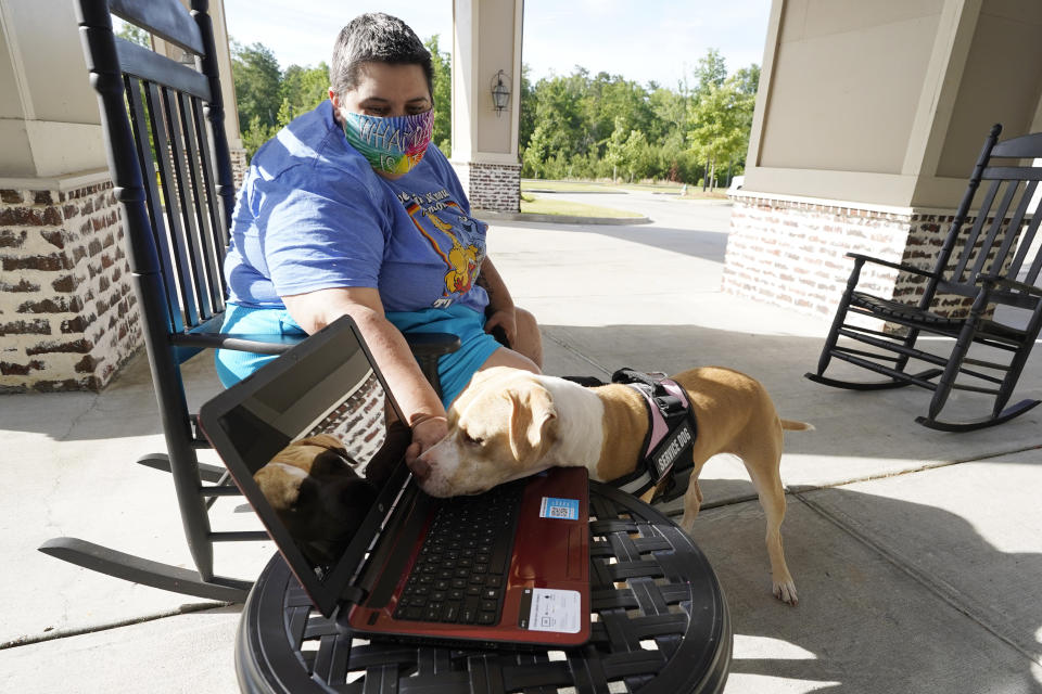 Katrina Folks lets her service dog, Princess, inspect her laptop, Friday, May 28, 2021, in Hattiesburg, Miss. Folks, who lost her job in September because of the coronavirus pandemic, used to do data entry at a law firm, but she has health issues that require her to work from home. Mississippi Gov. Tate Reeves announced May 10 that the state will opt out of the $300-a-week federal supplement for people who lost their jobs during the COVID-19 pandemic, as well as other programs that offered extended support for the unemployed, actions, directly affecting Folks. (AP Photo/Rogelio V. Solis)