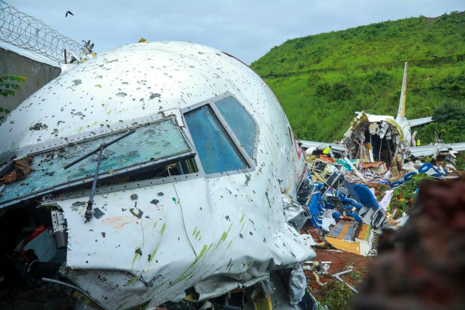 Officials inspect the wreckage of an Air India Express jet at Calicut International Airport in Karipur, Kerala, on August 8, 2020. - Fierce rain and winds lashed a plane carrying 190 people before it crash-landed and tore in two at an airport in southern India, killing at least 19 people and injuring scores more, officials said on August 8. (Photo by Arunchandra BOSE / AFP) (Photo by ARUNCHANDRA BOSE/AFP via Getty Images)