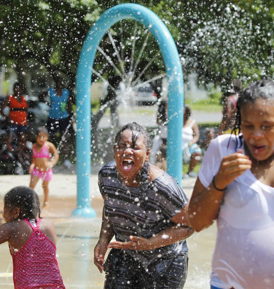 Emya Bennett, 10, Rochester, center, does her best to beat the heat by playing in the water at the Edgerton Community Center spray park as part of the city's Cool Sweep program Monday, June 30, 2014.  Locations throughout the city are open to help keep everyone cool as temps climb into the upper 80's all this week.