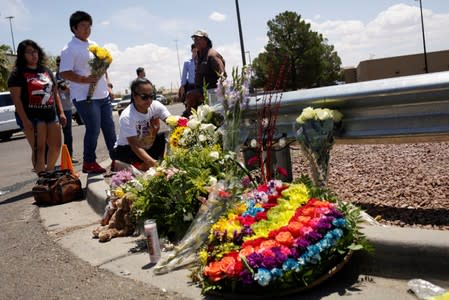 People place flowers at the site of a mass shooting where 20 people lost their lives at a Walmart in El Paso