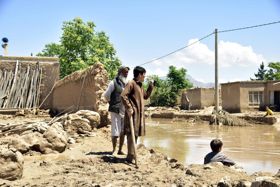 People stand near damaged homes after heavy flooding in Baghlan province in northern Afghanistan, Sunday, May 12, 2024. Victims of the devastating floods in northern Afghanistan are burying the dead and looking for the loved ones still missing. (AP Photo)