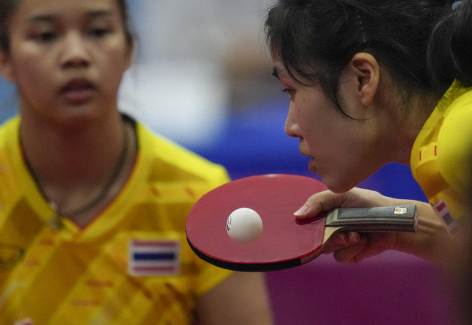 Thailand's Suthasini Sawettabut, right, returns a shot near Orawan Paranang against Singapore's Rui Juan Goi and Lin Qian Ser during their women's doubles semi final table tennis match at the 32nd Southeast Asian Games in Phnom Penh, Cambodia, Sunday, May 14, 2023. (AP Photo/Tatan Syuflana)