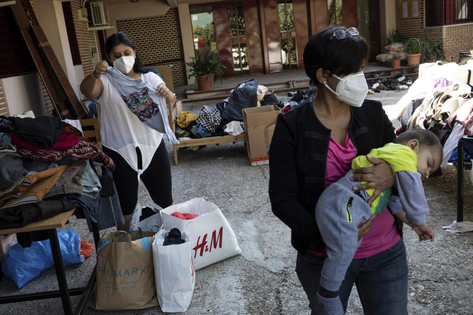 Residents of the southern neighbourhood of Vallecas pick clothes from a donation program at a Catholic parish in Madrid, Spain, Thursday, Oct. 1, 2020. Spain's government expects the economy to contract 11.2% this year, while the International Monetary Fund puts the drop at 12.8%, the highest rate among developed economies. (AP Photo/Bernat Armangue)