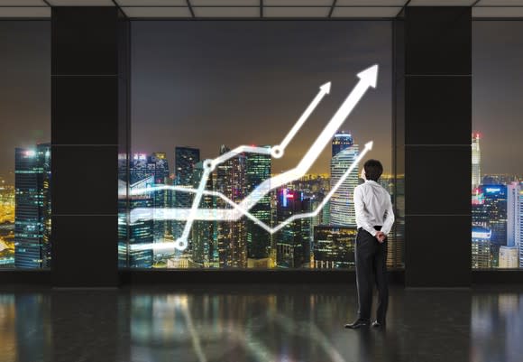 Man looking through window at three white lines going up with skyscrapers in background