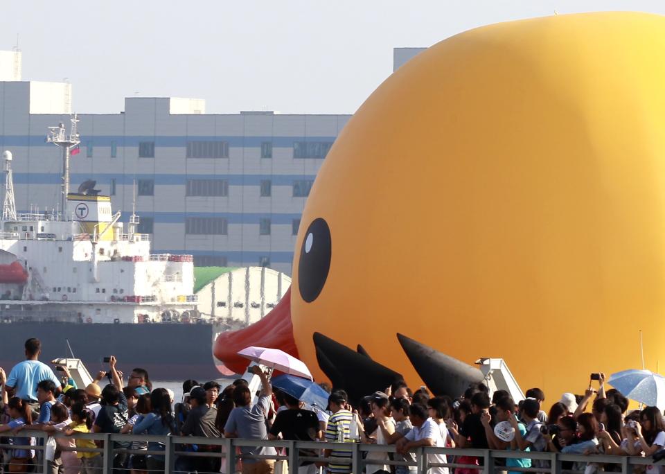 People take pictures of the "Rubber Duck" by Dutch conceptual artist Florentijn Hofman while it is pulled by tugboats at Kaohsiung Harbor, southern Taiwan, September 19, 2013. The giant rubber duck, which is 18 m (60 ft) high and weighs 1,000 kg (2,200 pounds), made its first public appearance in Taiwan on Thursday, It will be displayed at Kaohsiung Harbor from September 19 to October 20. REUTERS/Pichi Chuang (TAIWAN - Tags: SOCIETY)