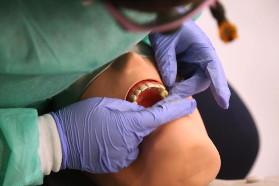 Somkene Okwuego inserts a crown on a mock patient.