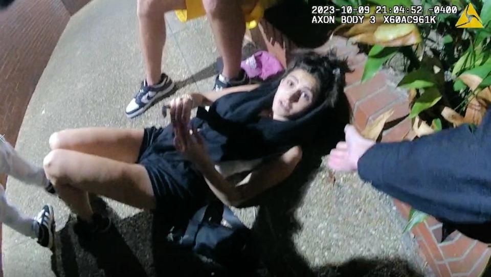 As seen on an image from her newly released video from her police body camera, University of Florida police Capt. Kristy Sasser extends her hand to assist an unidentified woman who said she fainted and inadvertently set off a panicked stampede during a nighttime vigil on campus Oct. 9, 2023, for Israelis killed in Hamas attacks. "I think it was me," said the woman, who said she was feeling weak before she blacked out. "I think I scared everybody."