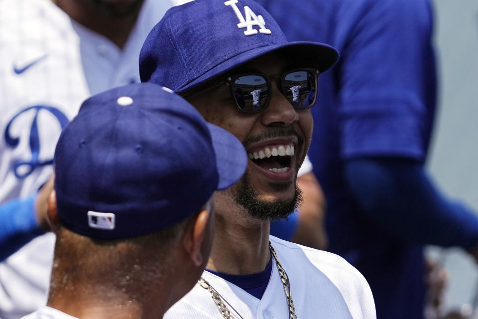 Los Angeles Dodgers' Mookie Betts, right, laughs as he talks to manager Dave Roberts in the dugout prior to a baseball game against the St. Louis Cardinals Sunday, April 30, 2023, in Los Angeles. (AP Photo/Mark J. Terrill)