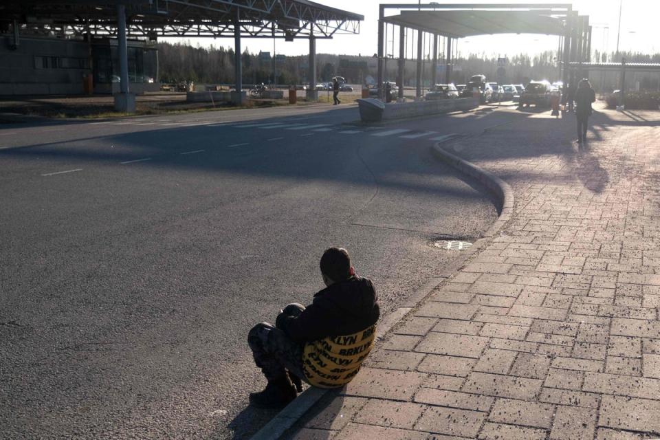 An asylum seeker sits in on the ground near the Nuijamaa border crossing between Finland and Russia, in Lappeenranta (AFP via Getty Images)