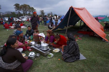 Family members eat their dinner in front of a makeshift shelter on open ground to keep safe after an earthquake in Kathmandu, Nepal April 26, 2015. REUTERS/Navesh Chitrakar