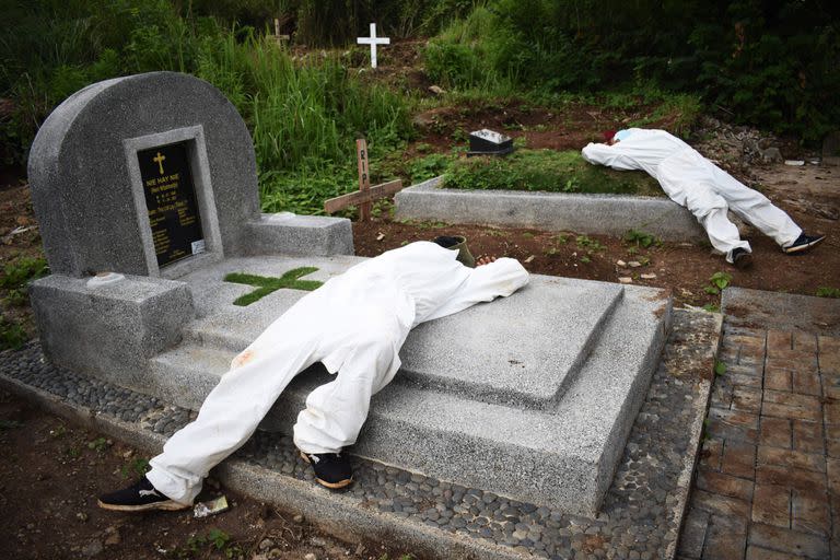Los excavadores de tumbas exhaustos descansan entre los funerales en un cementerio designado para las víctimas de Covid-19 en Bandung