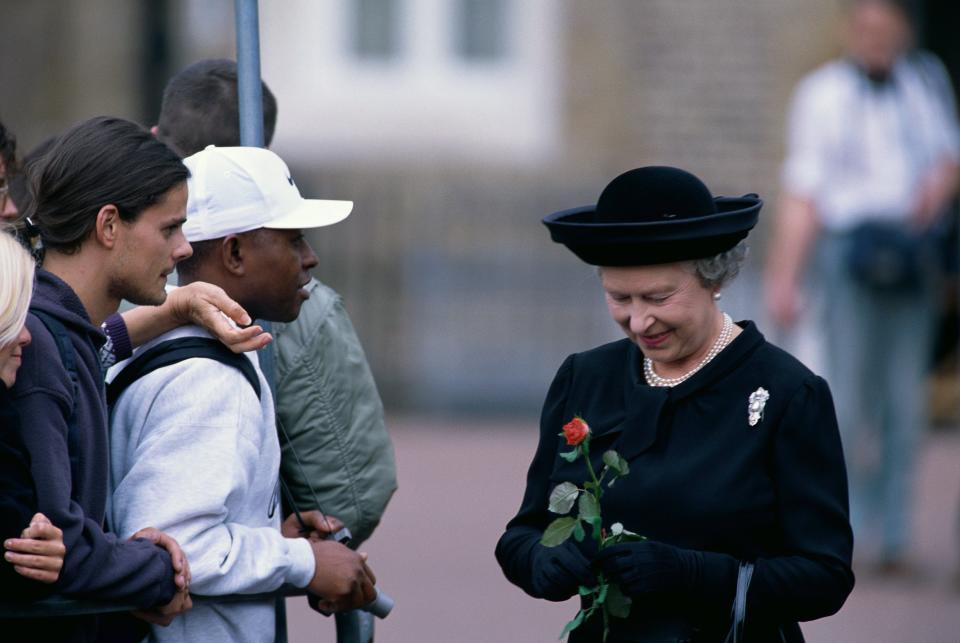 Queen Elizabeth, dressed in black, accepts a rose from mourners on the morning of Princess Diana's funeral.