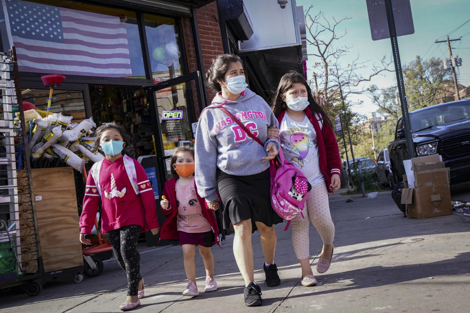 Pedestrians in masks pass a store on Thursday, Oct. 15, 2020, as government restrictions on business activity limit operations due to an increase of COVID-19 cases, in the Far Rockaway neighborhood of the borough of Queens in New York. After shutdowns swept entire nations during the first surge of the coronavirus earlier this year, some countries and U.S. states are trying more targeted measures as cases rise again around the world. (AP Photo/John Minchillo)