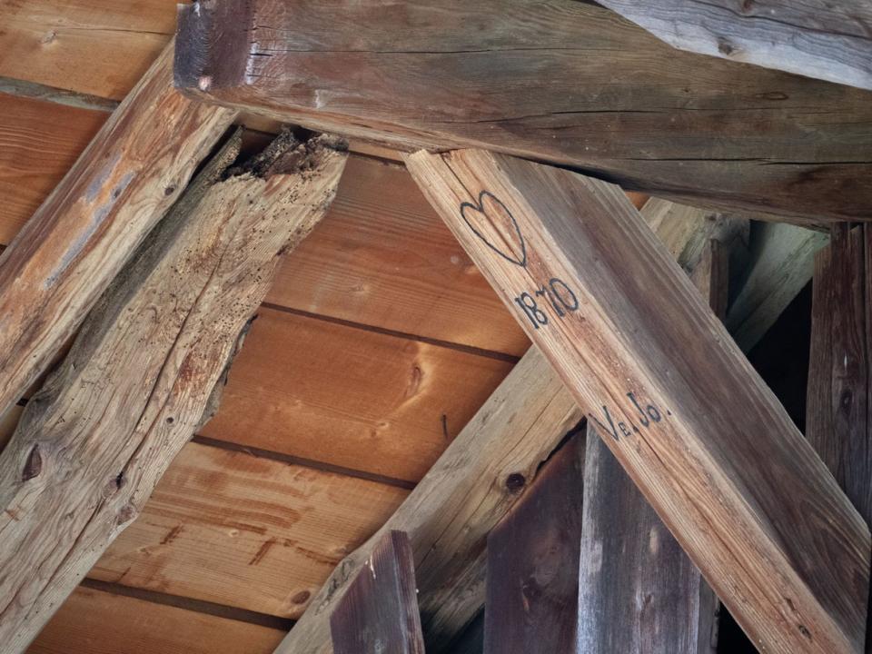 Wooden beam of a home with a date and heart carved on it. 