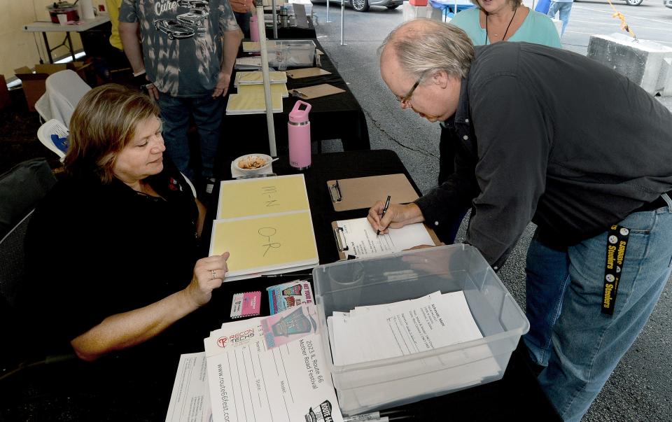 Cecil Renshaw of Springfield, right, registers for the Illinois Route 66 Mother Road Festival Thursday, Sept. 21, 2023, with Melissa Roberts an employee of Recon Tech, the title sponsor of the show.