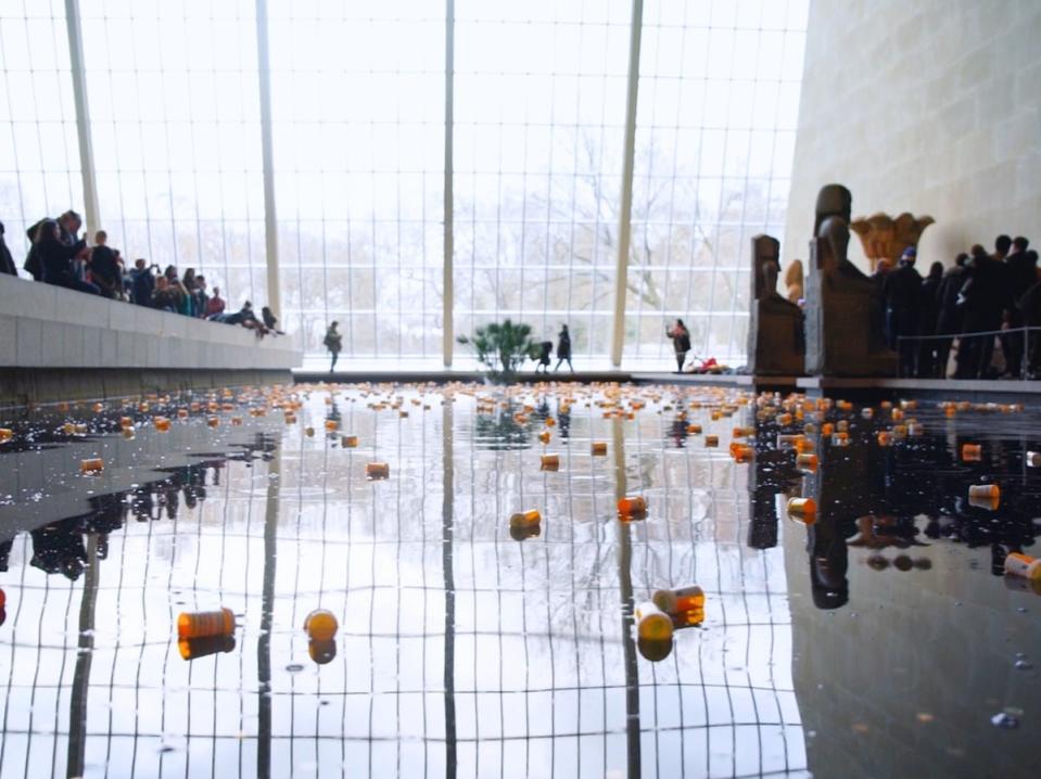 Pill bottles float in a decorate water feature as part of one of PAIN’s protests (Neon)