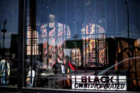 Ronald Cashaw looks out from the window of his clothing store, Just Kicking, in the Auburn Gresham neighborhood of Chicago, Saturday, Aug. 22, 2020. Blocked by security bars, looters smashed the front window of his store grabbed some clothing and ran away before Cashaw arrived. "I had tears in my eyes," says Cashaw. The looting was something new, and horrible. But in the nearly two decades Cashaw has served this community, financial problems have grown more devastating. (AP Photo/David Goldman)