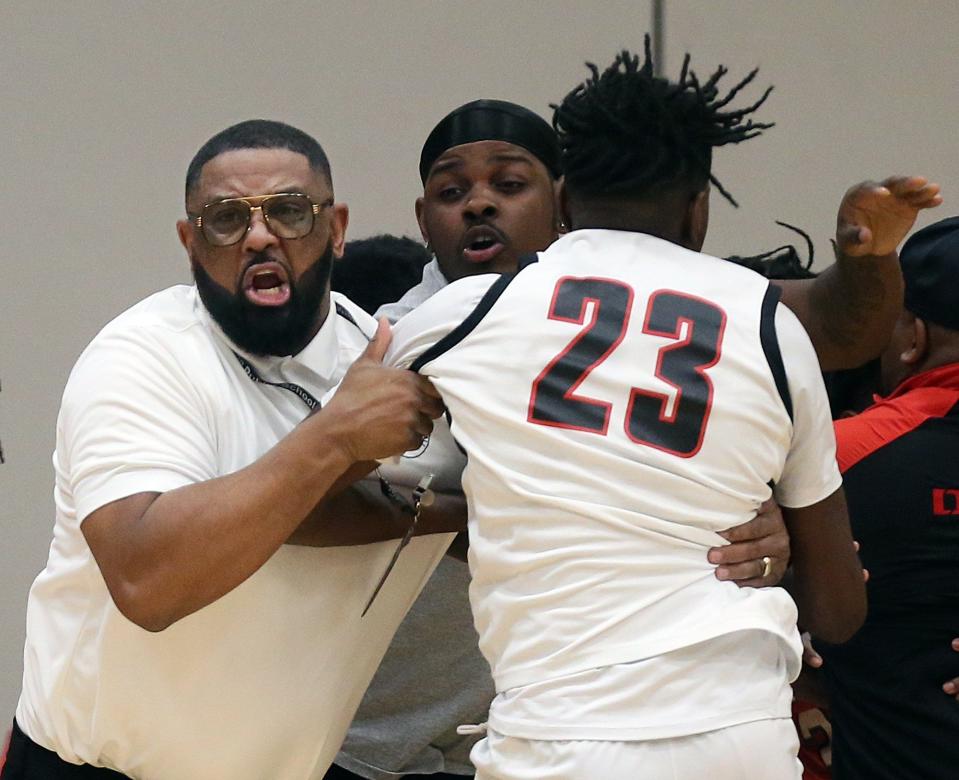 Buchtel basketball coach Rayshon Dent, facing, pulls Braylin Wells away from the brawl against East during the third quarter of a Division II district semifinal Wednesday night in North Ridgeville. [Jeff Lange/Beacon Journal]