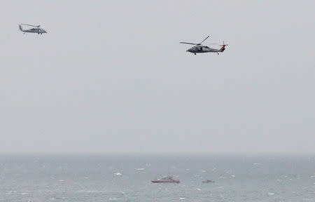 FILE PHOTO: A Iranian Revolutionary Guard boat is seen near the U.S. aircraft carrier, USS George H. W. Bush while transiting Straits of Hormuz as U.S. Navy helicopters hover over it during early hours of March 21, 2017. Picture taken March 21, 2017. REUTERS/Hamad I Mohammed