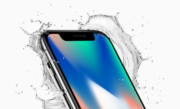 iPhone X with water splashing behind it.