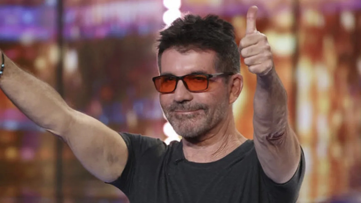  Simon Cowell in orange-tinted glasses giving the crowd two thumbs up on America's Got Talent. 