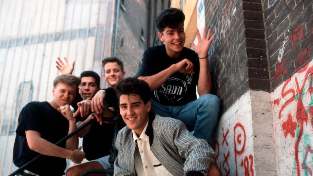 new kids on the block members donnie wahlberg, danny wood, joey mcintyre, jonathan knight, and jordan knight pose for a photo outside a brick building