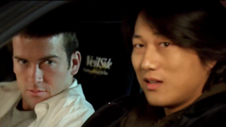 Lucase Black and Sung Kang looking out from their car in The Fast and the Furious: Tokyo Drift.