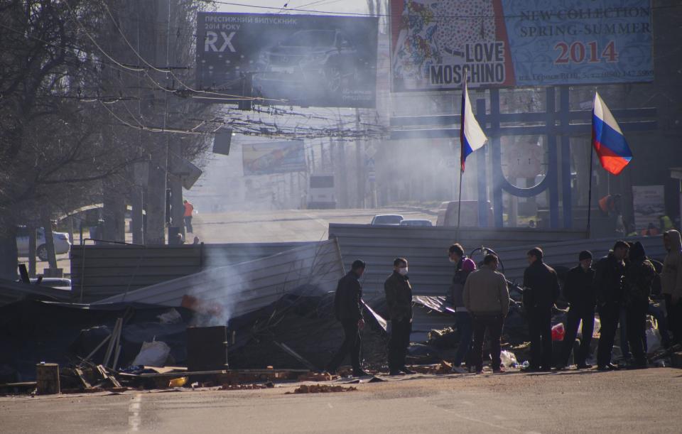 Pro-Russian activists gather behind a barricade with Russian flags in front an entrance of the Ukrainian regional office of the Security Service in Luhansk, 30 kilometers (20 miles) west of the Russian border, in Ukraine, Tuesday, April 8, 2014. A crowd of pro-Russian activists stormed the building on Sunday, April 6, 2014. Local media reported that demonstrators pelted the building with eggs, and then stones, a smoke grenade and finally a firebomb. The flames were reportedly quickly extinguished. (AP Photo/Igor Golovniov)