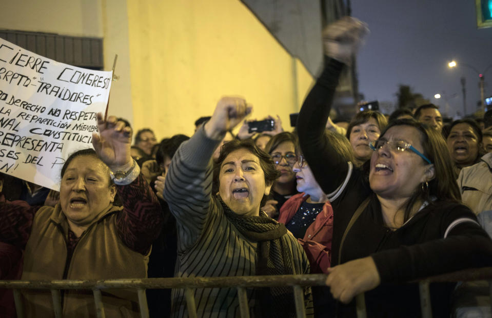 Demonstrators who had gathered to protest against lawmakers pushing forward a vote to select an almost-full slate of new magistrates to the Constitutional Tribunal, celebrate outside Congress after President Martin Vizcarra dissolved the legislature in Lima, Peru, Monday, Sept. 30, 2019. Lawmakers were pushing forward the vote despite Vizcarra's warning that the move threatens his fight against corruption and that he would dissolve the opposition-controlled legislature. (AP Photo/Rodrigo Abd)