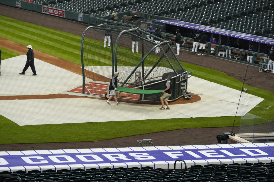 Grounds crew workers prepare to pull the tarpulin as a light rain descends on Coors Field Tuesday, April 6, 2021, before the Colorado Rockies host the Arizona Diamondbacks in a baseball game in Denver. Major League Baseball announced that Coors Field will be the venue for the 2021 All Star Game after the Midsummer Classic was moved out of Atlanta because of sweeping changes to voting rights established in the state of Georgia. (AP Photo/David Zalubowski)