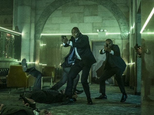 Lance Reddick as Charon shooting enemies in the Continental.