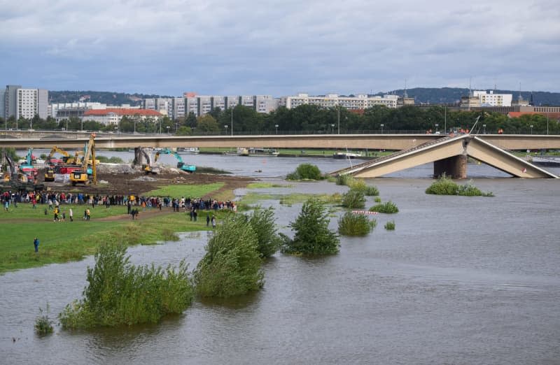 Numerous spectators watch as the collapsed Carola Bridge on the banks of the Elbe is demolished. Robert Michael/dpa